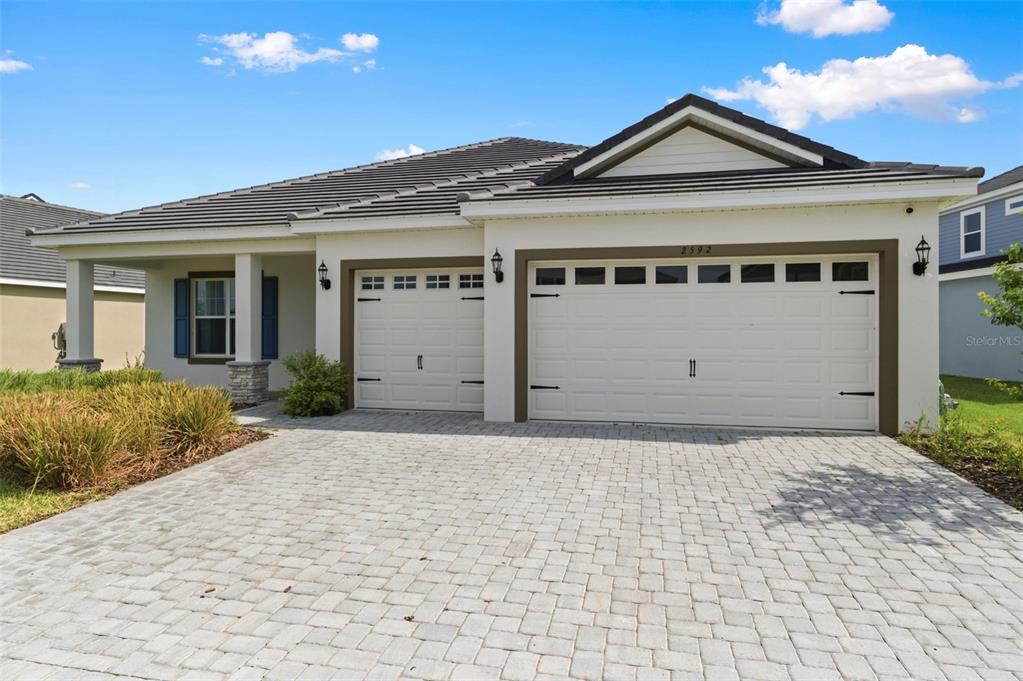 A single-story house with a paved driveway, a three-car garage, and blue shutters — 2592 WISE RIVER LANE, ZEPHYRHILLS, FL