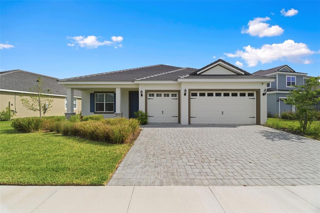 A single-story house with a paved driveway, two garage doors, and a landscaped front yard — 2592 WISE RIVER LANE, ZEPHYRHILLS, FL
