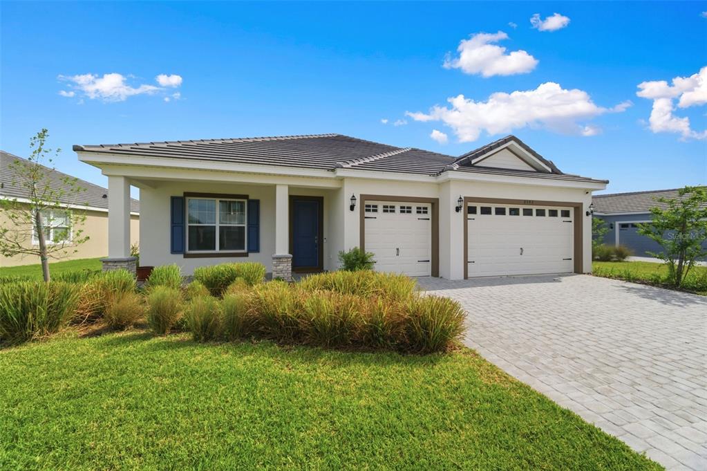 A single-story house with a tiled roof, blue front door, and a two-car garage — 2592 WISE RIVER LANE, ZEPHYRHILLS, FL