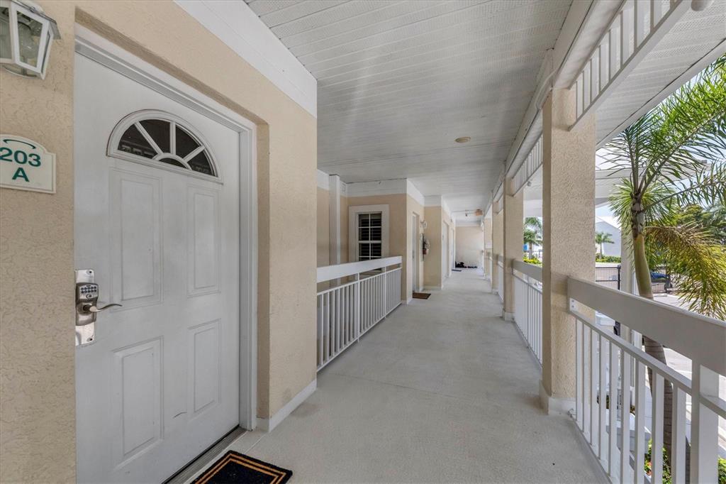 An outdoor covered walkway leads to a white front door labeled 203 A — 3401 54TH DRIVE W UNIT 203, BRADENTON, FL