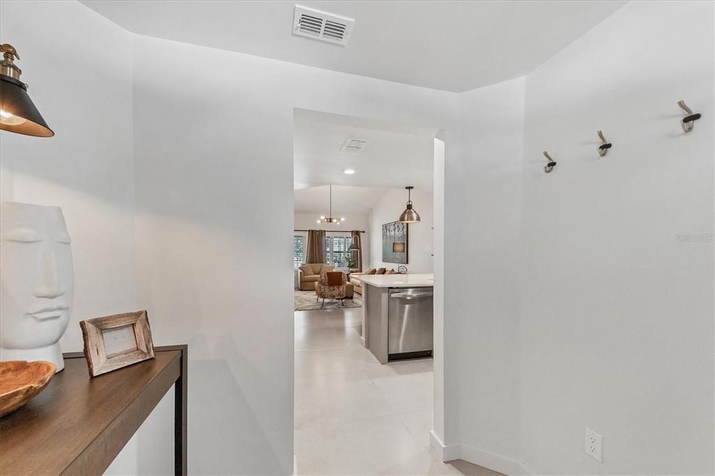A hallway leads into an open-concept kitchen and living area with light tile flooring — 3401 54TH DRIVE W UNIT 203, BRADENTON, FL