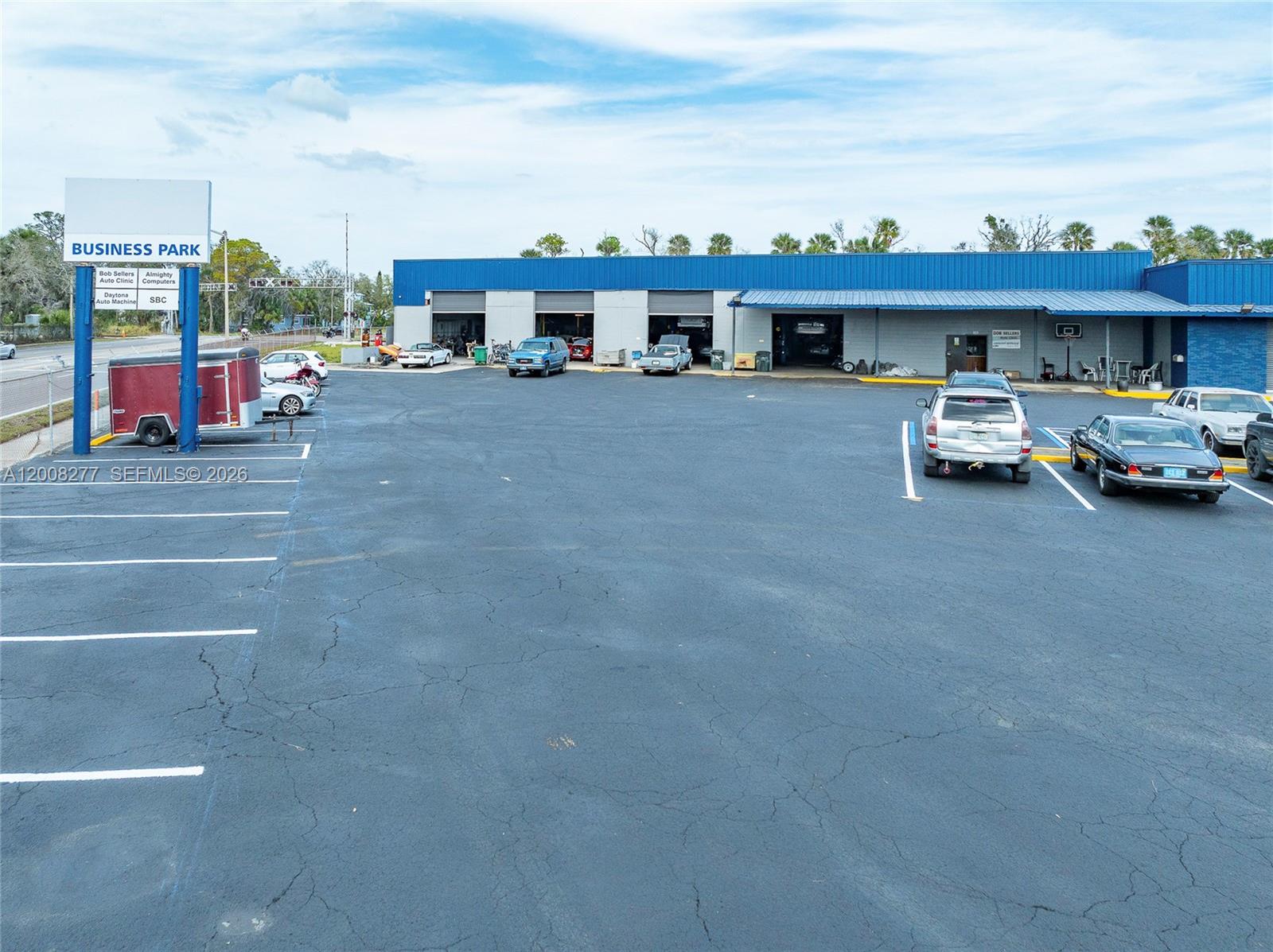 An aerial view shows a commercial building with several garage bays and a parking lot — 405 N Charles St, Daytona FL 32114, DAYTONA, FL