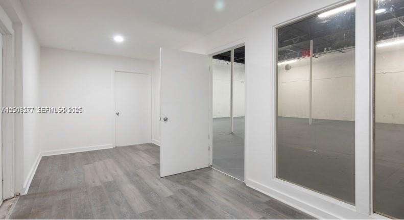 An interior view shows a room with gray wood-look flooring, white walls, and glass partitions — 405 N Charles St, Daytona FL 32114, DAYTONA, FL
