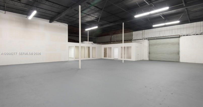 An empty industrial warehouse space features a gray concrete floor, white walls, and office partitions — 405 N Charles St, Daytona FL 32114, DAYTONA, FL