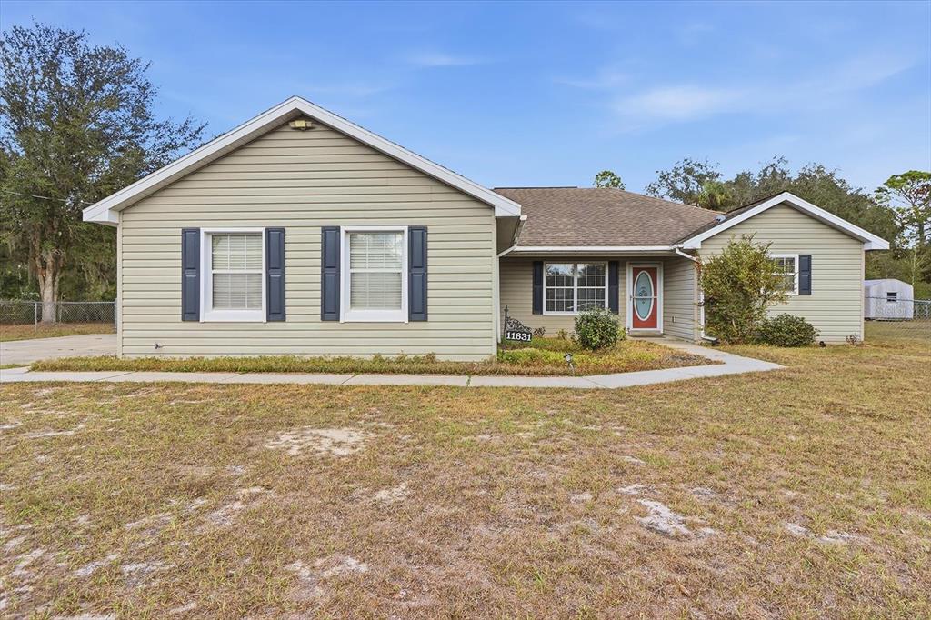 A single-story house with light green siding, dark shutters, and a red front door — 11631 SE 195TH PLACE, DUNNELLON, FL