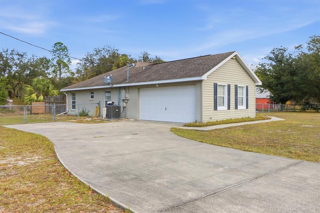 A single-story house with beige siding, a white garage door, and a concrete driveway — 11631 SE 195TH PLACE, DUNNELLON, FL