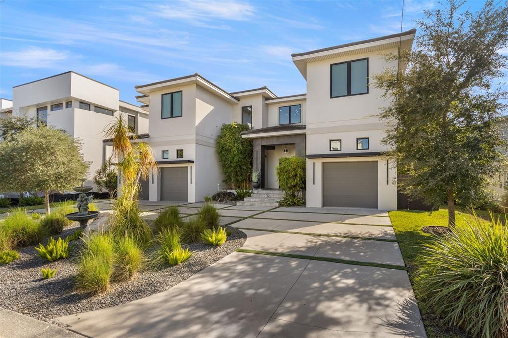 A modern two-story house features a concrete driveway, a stone entryway, and landscaped front gardens — 4924 W SAN RAFAEL STREET, TAMPA, FL