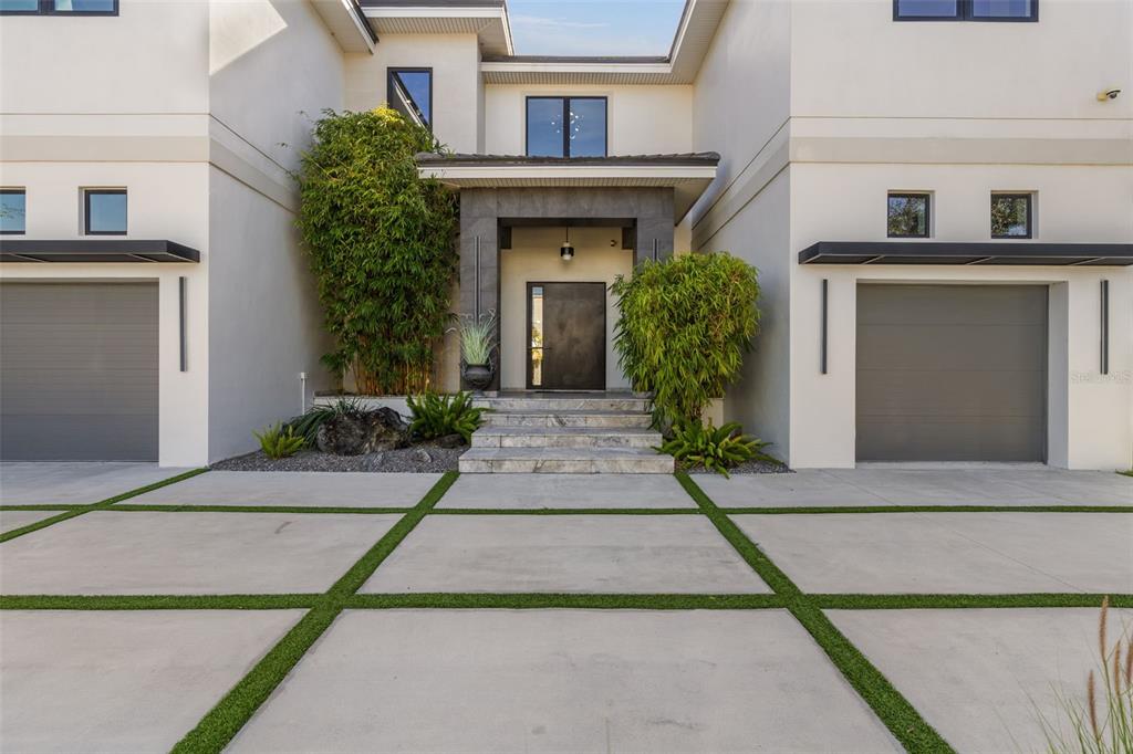 The exterior of a modern two-story home features a concrete driveway and a covered entrance — 4924 W SAN RAFAEL STREET, TAMPA, FL