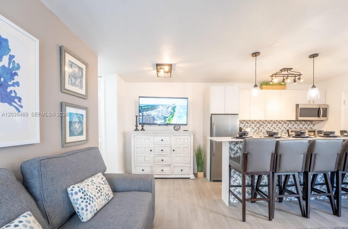 A living room features a gray sofa, a white media console, and an open kitchen — 7834 abbott ave # 7, Miami Beach FL 33141, MIAMI BEACH, FL