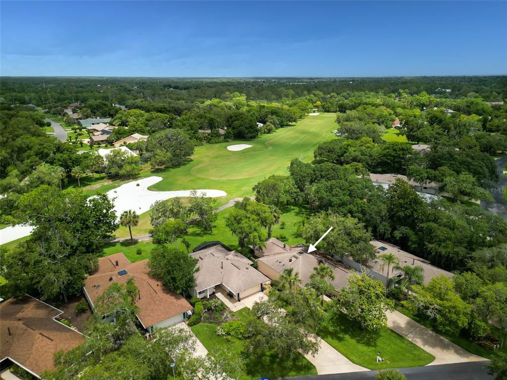 An aerial view shows a residential house with a roof arrow pointing toward a golf course — 718 TANTALLON COURT, NEW SMYRNA BEACH, FL