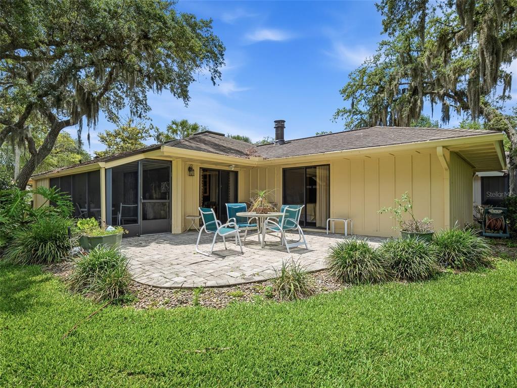 A yellow house with a paved patio, outdoor furniture, and a screened-in porch — 718 TANTALLON COURT, NEW SMYRNA BEACH, FL