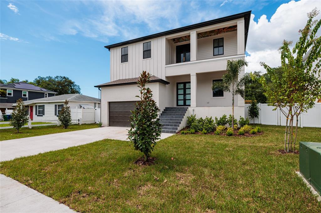 A two-story house features a white brick garage, vertical siding, and a covered front porch — 4705 W KNIGHTS AVENUE, TAMPA, FL
