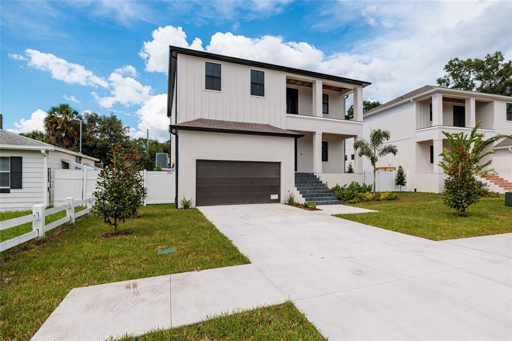 A two-story house with a white brick garage, vertical siding, and a covered front porch — 4705 W KNIGHTS AVENUE, TAMPA, FL