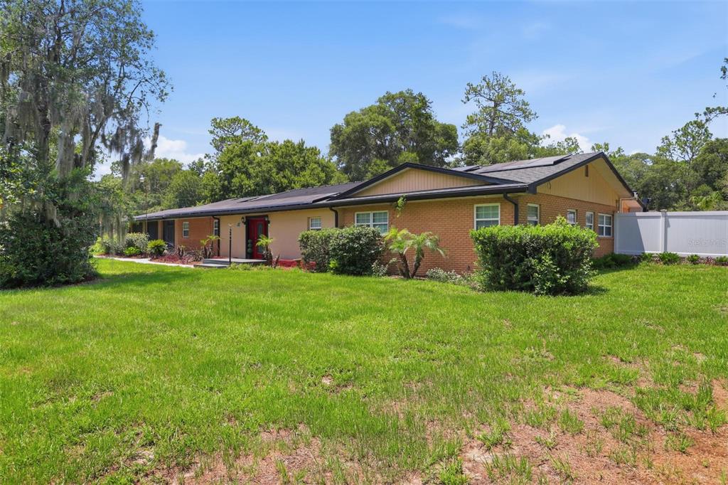A single-story brick house with a red front door sits on a grassy lot — 1570 GLENWOOD ROAD, DELAND, FL