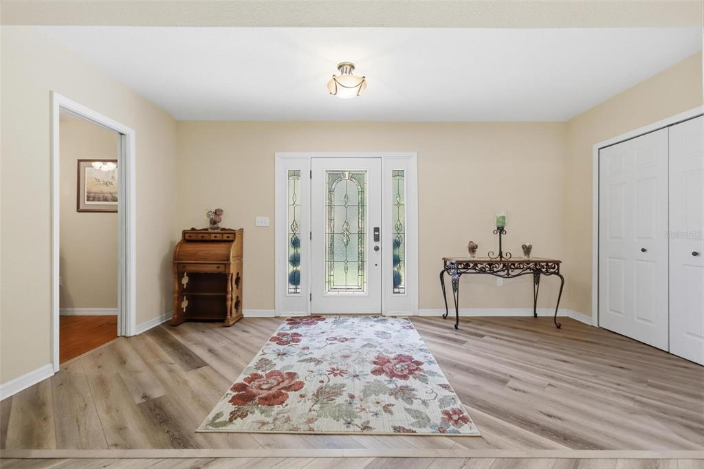 An entryway features light wood-look flooring, a floral area rug, and a white front door — 1570 GLENWOOD ROAD, DELAND, FL