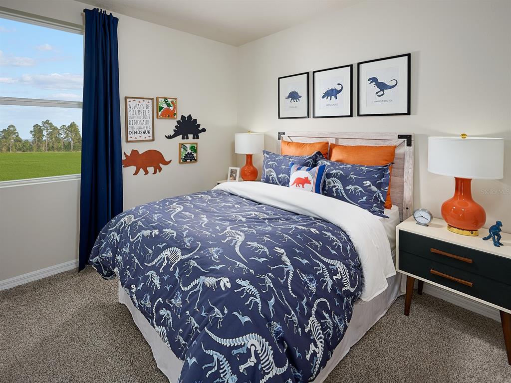 A bedroom features dinosaur-themed bedding, wall art, and orange lamps on a nightstand — 3505 BROADWING BOULEVARD, POINCIANA, FL