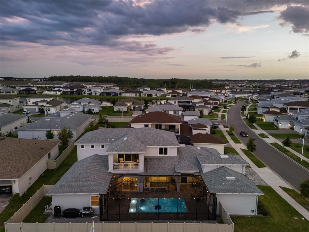 An aerial view of a two-story suburban house featuring a screened-in pool and patio — 8776 IVY STARK BOULEVARD, WESLEY CHAPEL, FL