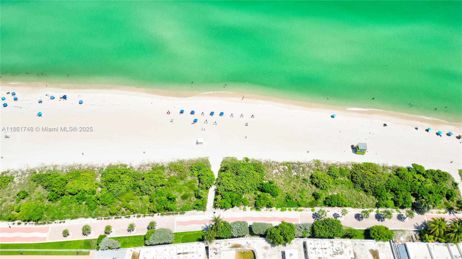 An aerial view shows a sandy beach with blue umbrellas, green vegetation, and a paved path — 5640 Collins Ave # 6B, Miami Beach FL 33140, MIAMI BEACH, FL