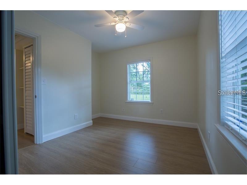 This bedroom features light-colored walls, wood-look flooring, a ceiling fan, and a walk-in closet — 908 W OHIO AVENUE, TAMPA, FL