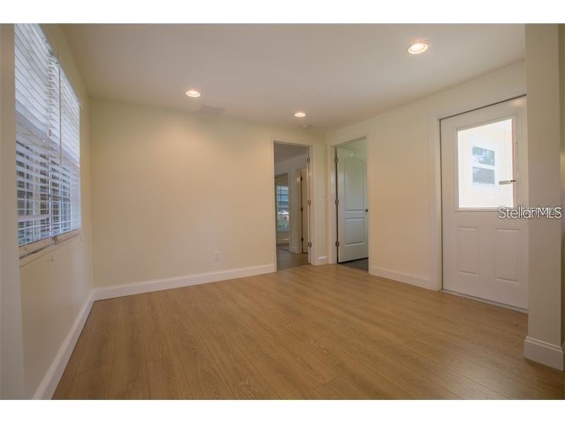 An empty room features light wood-look flooring, white walls, recessed lighting, and a glass-paneled door — 908 W OHIO AVENUE, TAMPA, FL