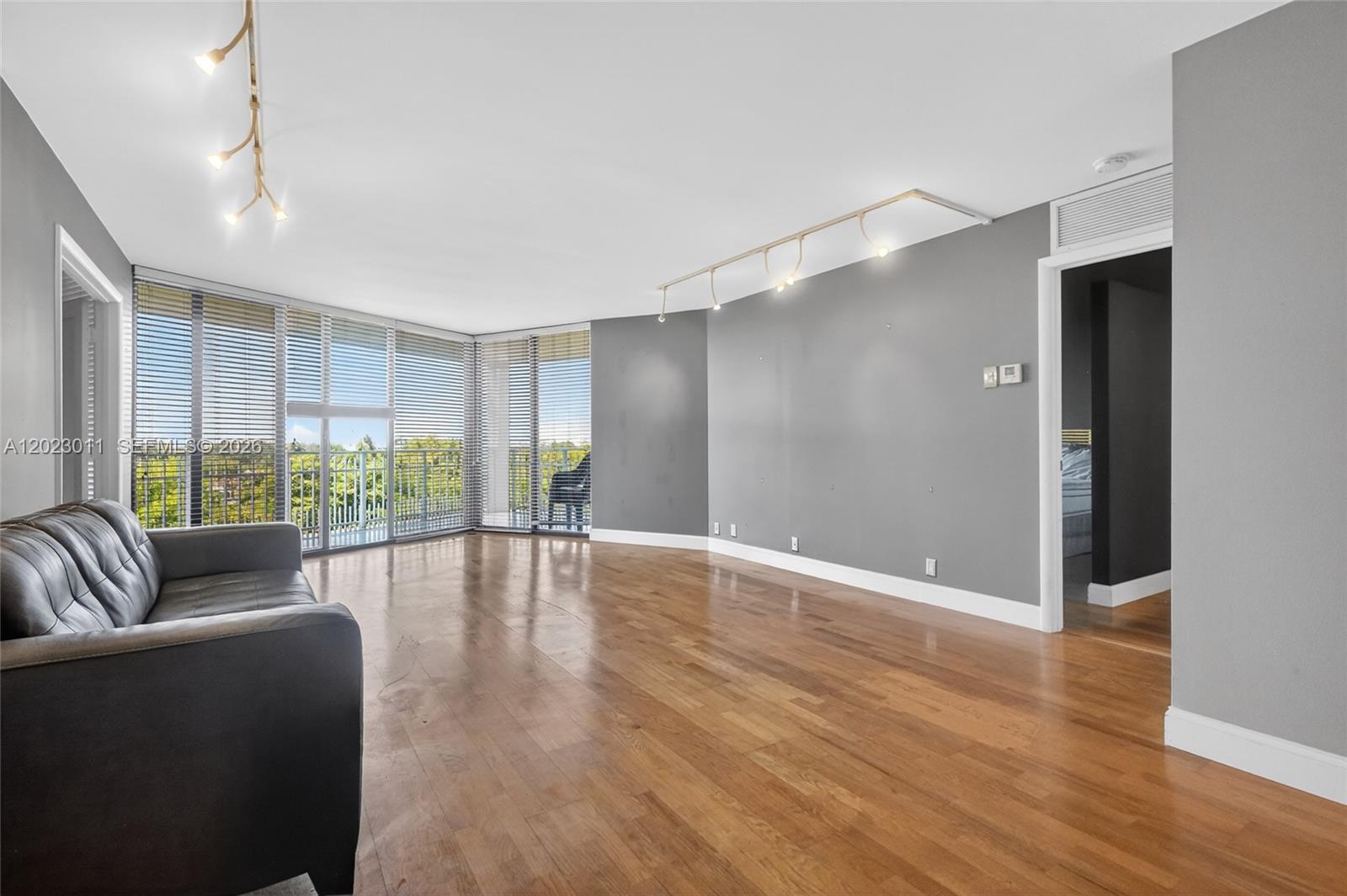 A living room features hardwood floors, a gray accent wall, and floor-to-ceiling windows — 2000 Towerside Ter # 709, Miami FL 33138, MIAMI, FL