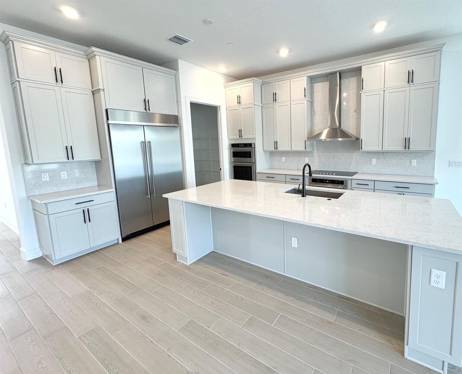 A modern kitchen features light gray cabinetry, a large quartz island, and stainless steel appliances — 8225 Nilsa Place # 39, Davie FL 33328, DAVIE, FL
