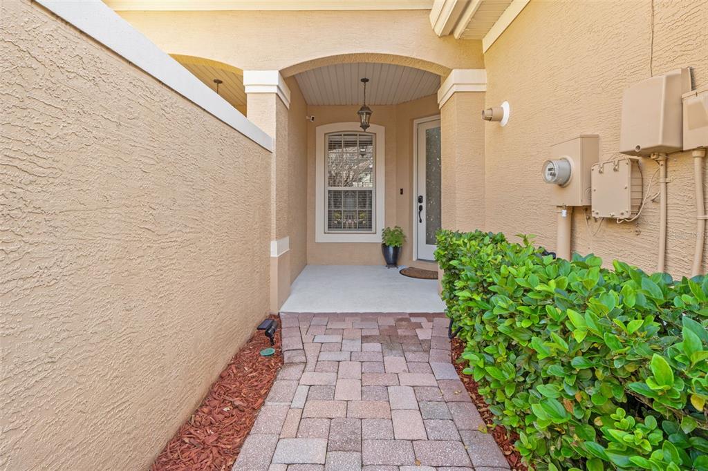 A paved walkway leads to a covered entryway with a front door and a window — 7305 GABERIA ROAD, NEW PORT RICHEY, FL