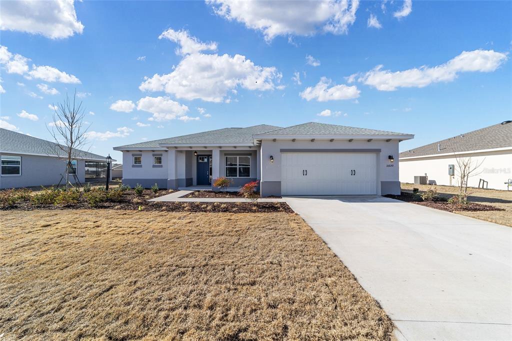 A single-story house with a white garage, gray exterior, and a concrete driveway — 10650 SW 101ST LANE ROAD, OCALA, FL