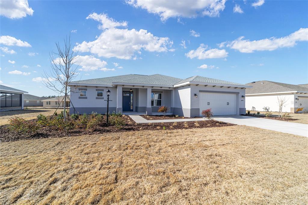 A single-story house with a light-colored stucco exterior, a two-car garage, and a front porch — 10650 SW 101ST LANE ROAD, OCALA, FL