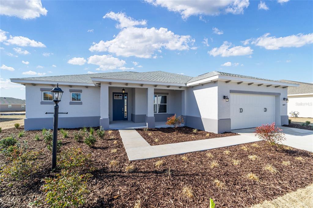 A single-story house with a white stucco exterior, a two-car garage, and a front porch — 10650 SW 101ST LANE ROAD, OCALA, FL