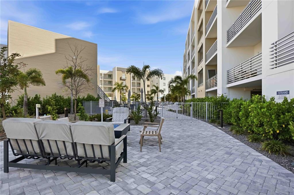 An outdoor patio area features a sofa, chairs, and a fire pit near a building — 1703 N TAMIAMI TRAIL UNIT 406, SARASOTA, FL