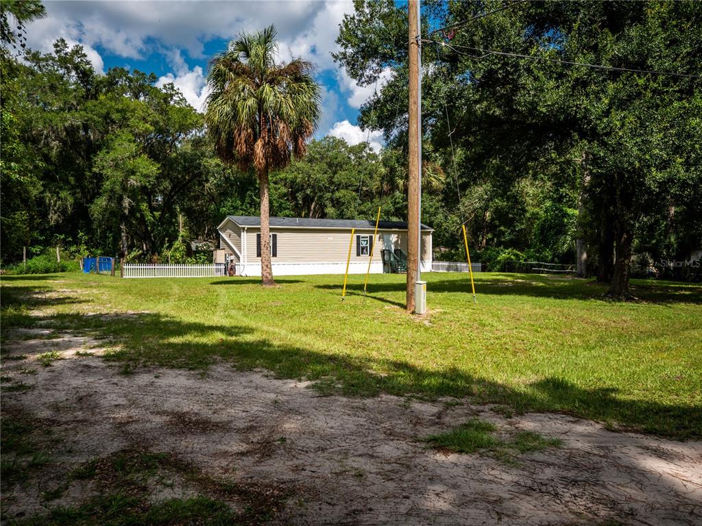 A single-story manufactured home sits on a grassy lot with a palm tree and utility pole — 14388 NE 116TH TERRACE, FORT MC COY, FL
