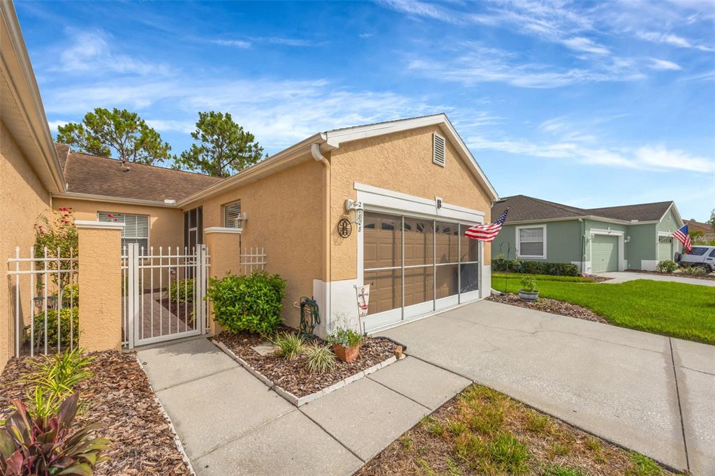 A tan stucco house with a two-car garage and a gated front courtyard entrance — 20828 EUSTIS ROAD, LAND O LAKES, FL