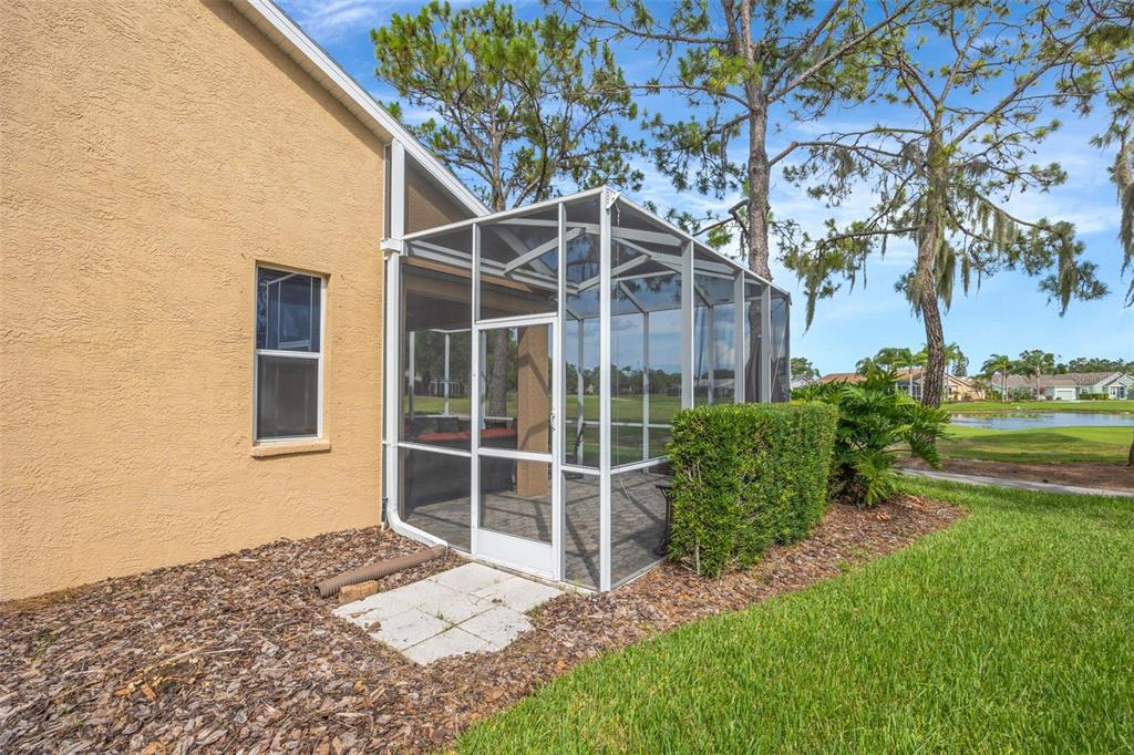 A tan house exterior features a screened-in patio enclosure next to a small hedge — 20828 EUSTIS ROAD, LAND O LAKES, FL