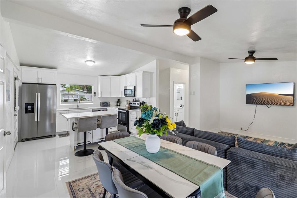 An open-concept kitchen and dining area features white cabinetry, a kitchen island, and ceiling fans — 160 PONCE DE LEON DRIVE, ORMOND BEACH, FL