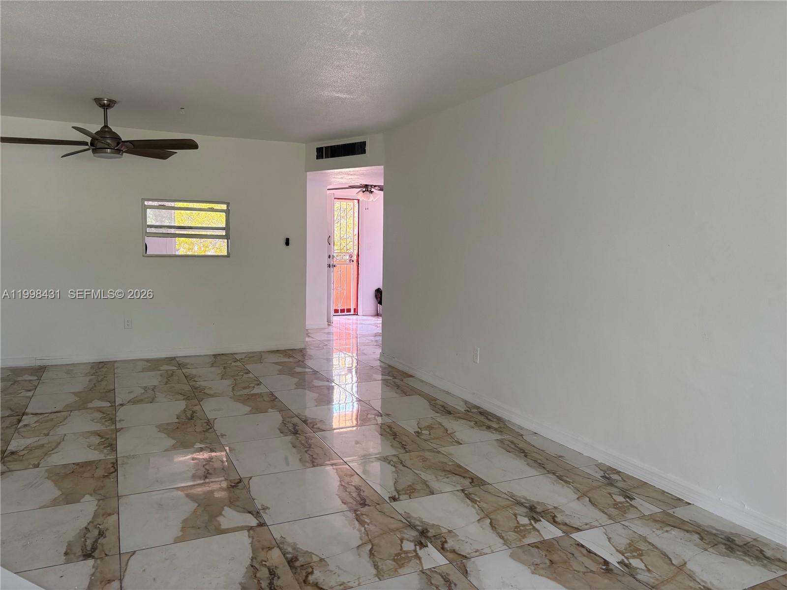 A room with white walls, a ceiling fan, and large, brown-veined marble-style floor tiles — 1501 NE 191st St # C211, Miami FL 33179, MIAMI, FL
