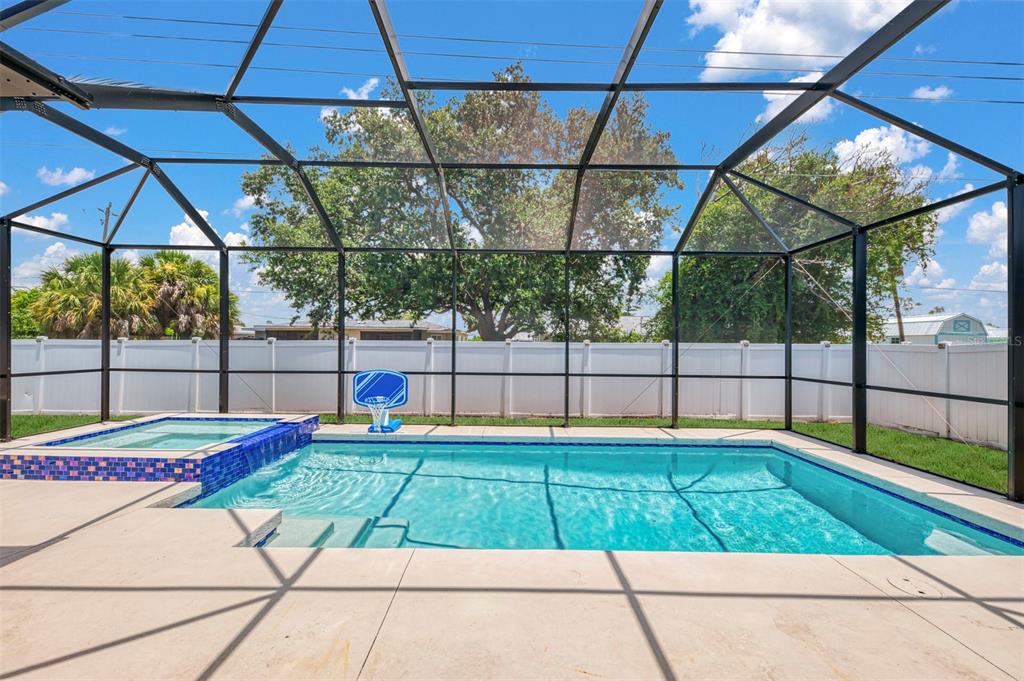 A swimming pool and spa are enclosed within a screened lanai with a white fence — 4327 MANFIELD DRIVE, VENICE, FL