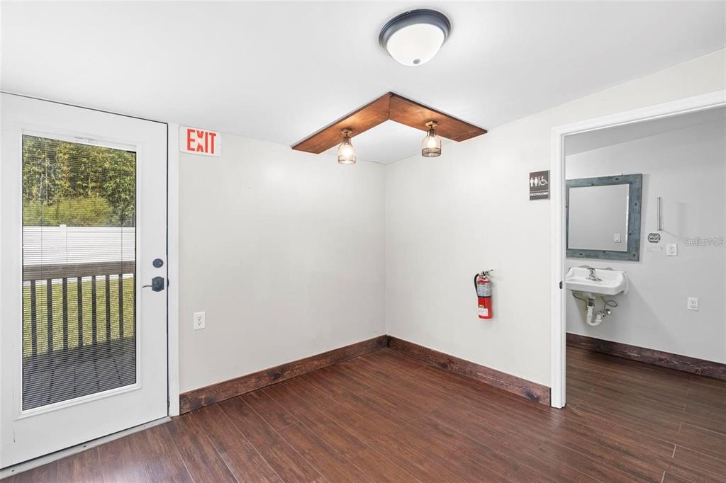 A room with wood-look flooring, a wooden light fixture, a fire extinguisher, and a restroom — 329 FRANKLIN STREET, OCOEE, FL