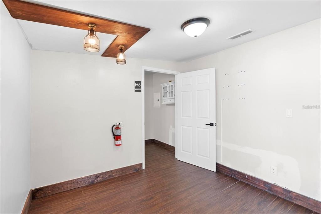 An interior room features wood-look flooring, a wooden ceiling beam with pendant lights, and a fire extinguisher — 329 FRANKLIN STREET, OCOEE, FL