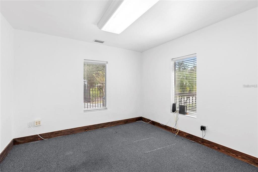 An empty room with white walls, dark carpet, dark wood baseboards, and two windows — 329 FRANKLIN STREET, OCOEE, FL