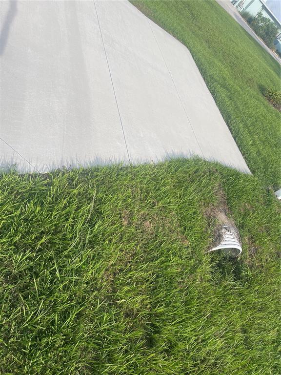 A concrete driveway edge meets a grassy lawn with a small drainage pipe outlet — 11109 SUNNYDALE AVENUE, ENGLEWOOD, FL