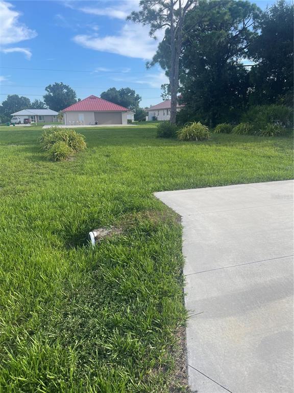 A grassy residential lot features a concrete driveway and a white pipe near the edge — 11109 SUNNYDALE AVENUE, ENGLEWOOD, FL