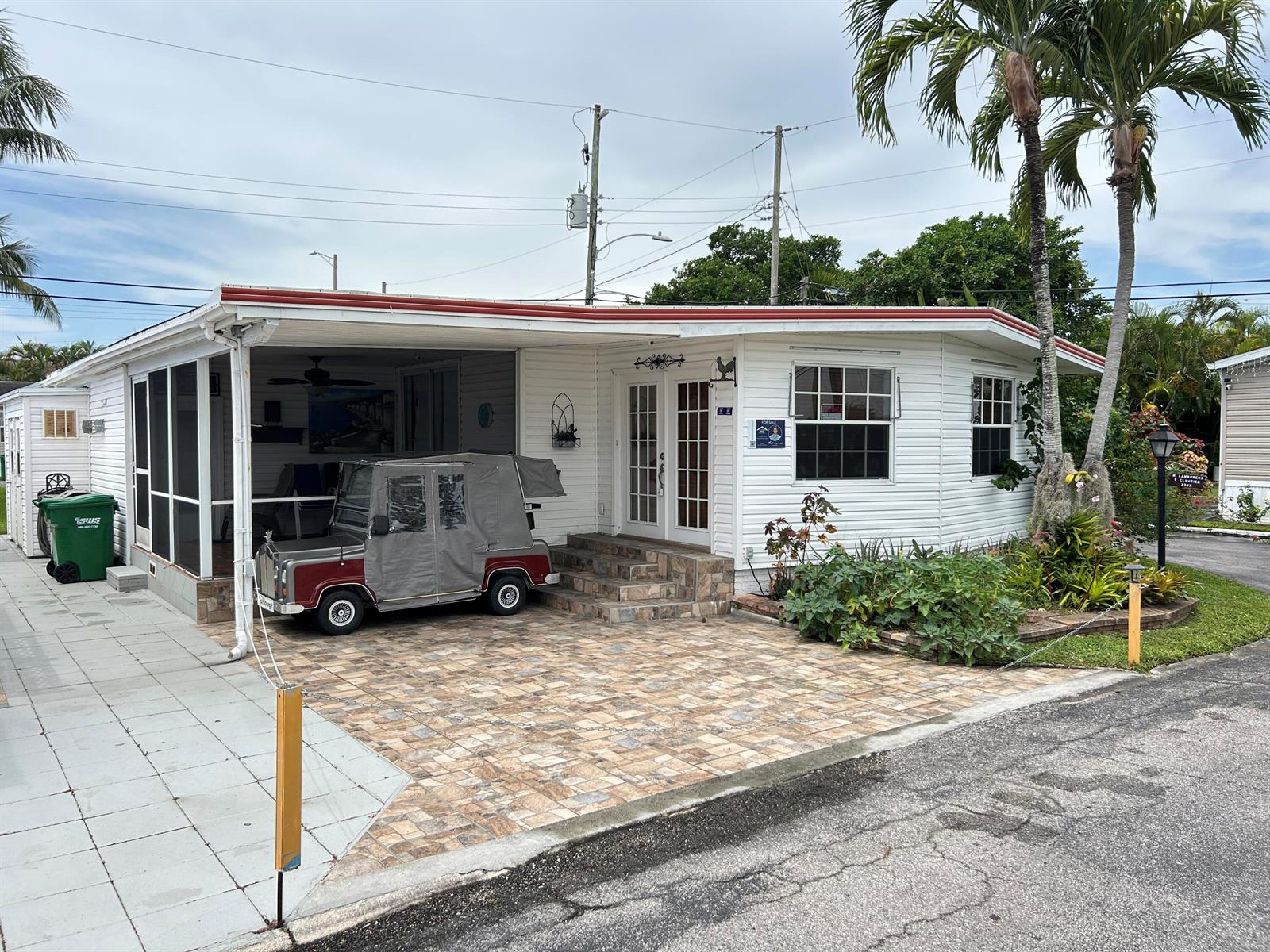 A white mobile home with a paved driveway, carport, and a small golf cart parked outside — 3348 Florida Street, Hollywood FL 33021, HOLLYWOOD, FL