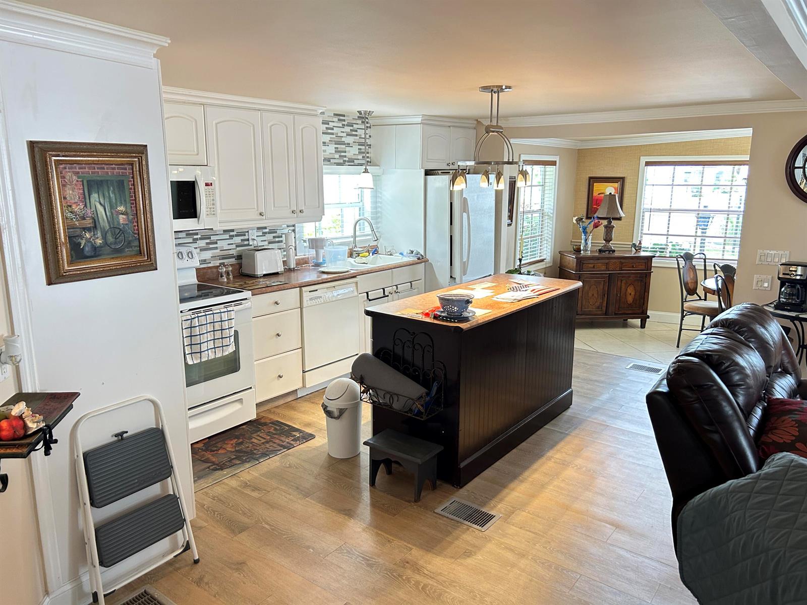 A kitchen features white cabinetry, a dark wood island, and light wood-look flooring — 3348 Florida Street, Hollywood FL 33021, HOLLYWOOD, FL