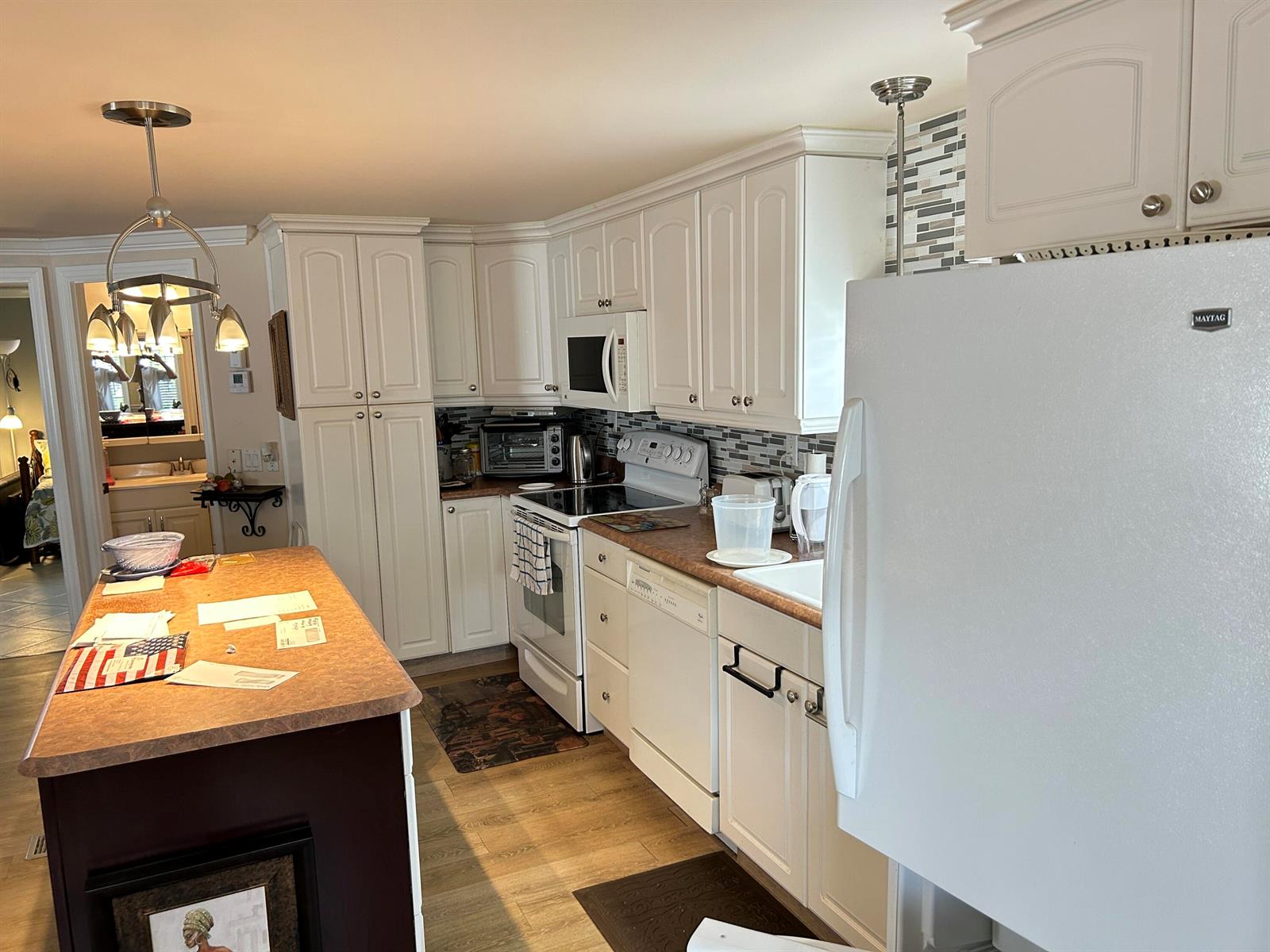A kitchen features white cabinetry, a dark-topped island, and a white refrigerator — 3348 Florida Street, Hollywood FL 33021, HOLLYWOOD, FL