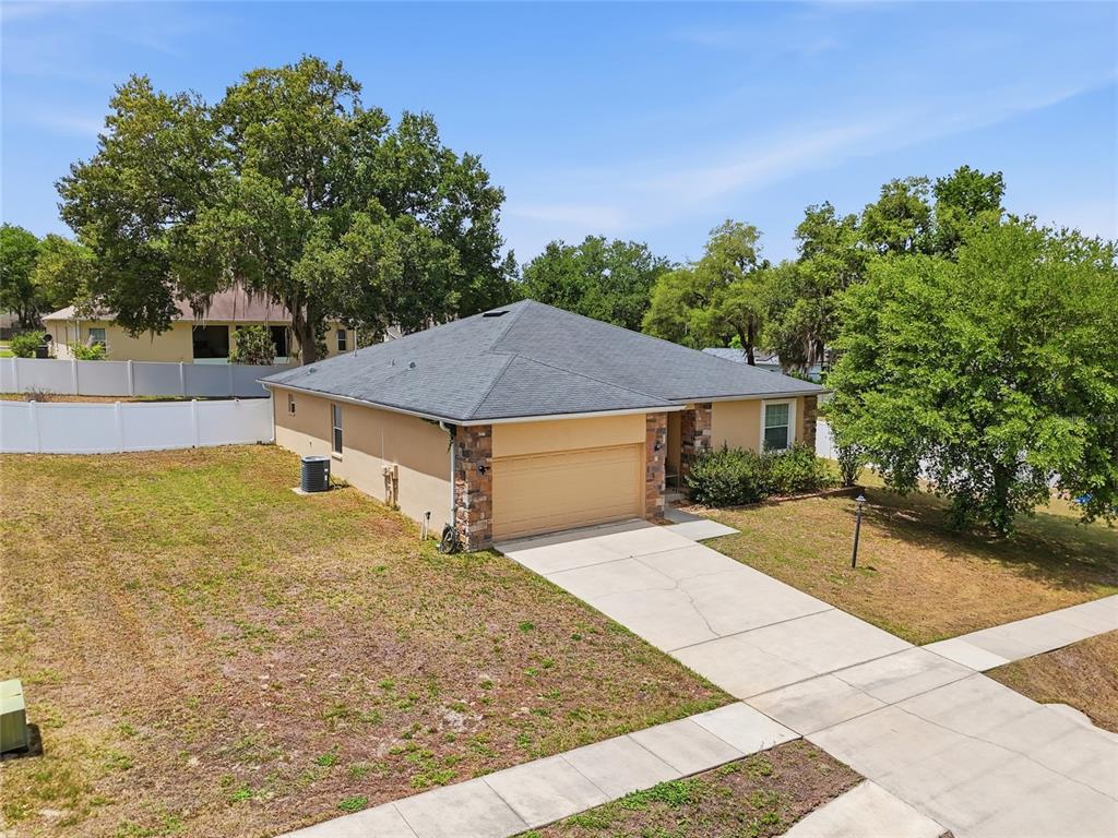 A single-story house with a tan stucco exterior, stone accents, and a concrete driveway — 306 STONEPOINT LANE, LADY LAKE, FL