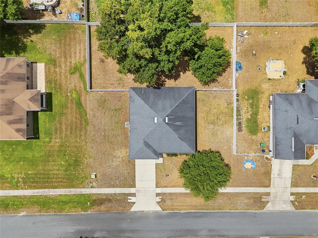 An aerial view shows a house with a dark roof, a driveway, and fenced yards — 306 STONEPOINT LANE, LADY LAKE, FL