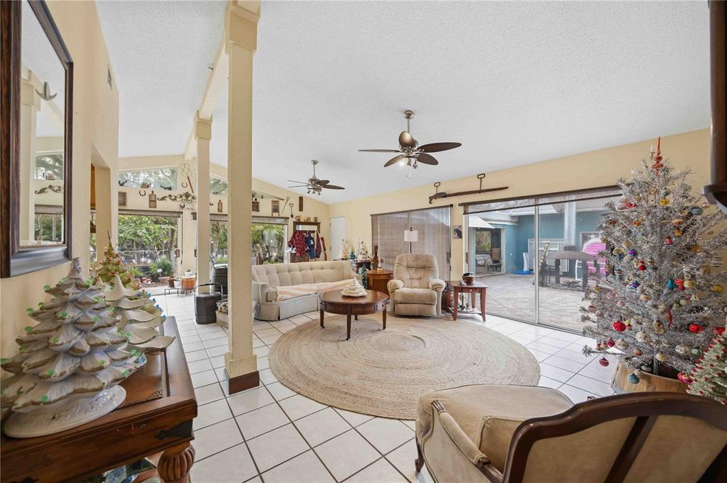 A living room with tile floors, two ceiling fans, and a view of a pool — 6649 PIMLICO STREET, NORTH PORT, FL