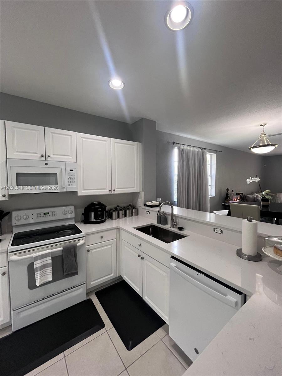 A kitchen features white cabinets, stainless steel appliances, and a peninsula with a sink — 681 NW 42nd Ave, Plantation FL 33317, PLANTATION, FL