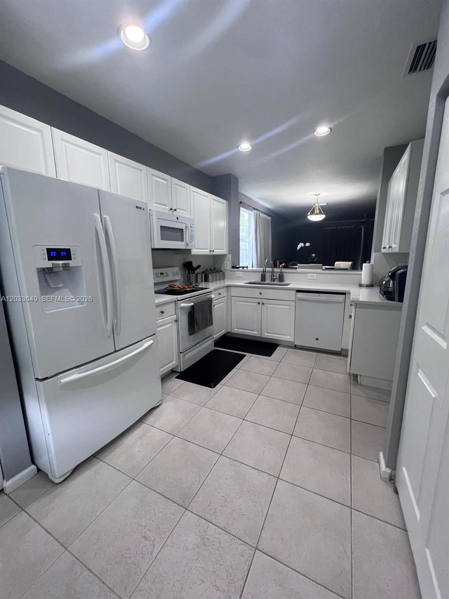 A white kitchen features tile flooring, white cabinetry, and stainless steel appliances — 681 NW 42nd Ave, Plantation FL 33317, PLANTATION, FL